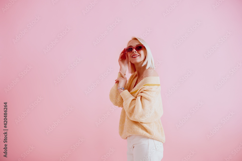 Happy smiling lady wearing trendy pink sunglasses, yellow  sweater, stylish silver wrist watch, posing on pink background. Spring fashion conception. Copy, empty space for text
 - obrazy, fototapety, plakaty 