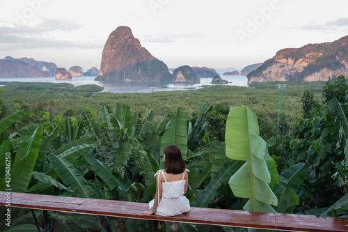 Happy traveler woman enjoy Phang Nga bay view point, alone Tourist sitting and relaxing at Samet Nang She, near Phuket in Southern Thailand. Southeast Asia travel, trip and summer vacation concept