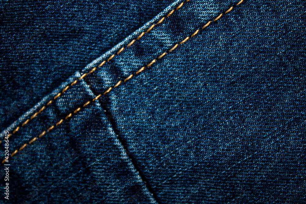 Background on the theme of denim clothing. Denim fabric with elements of seams. Background on the theme of denim clothing. Denim fabric with elements of seams.