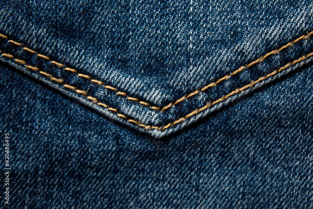 Background on the theme of denim clothing. Denim fabric with elements of seams.