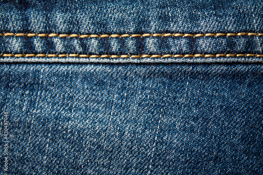 Background on the theme of denim clothing. Denim fabric with elements of seams.
