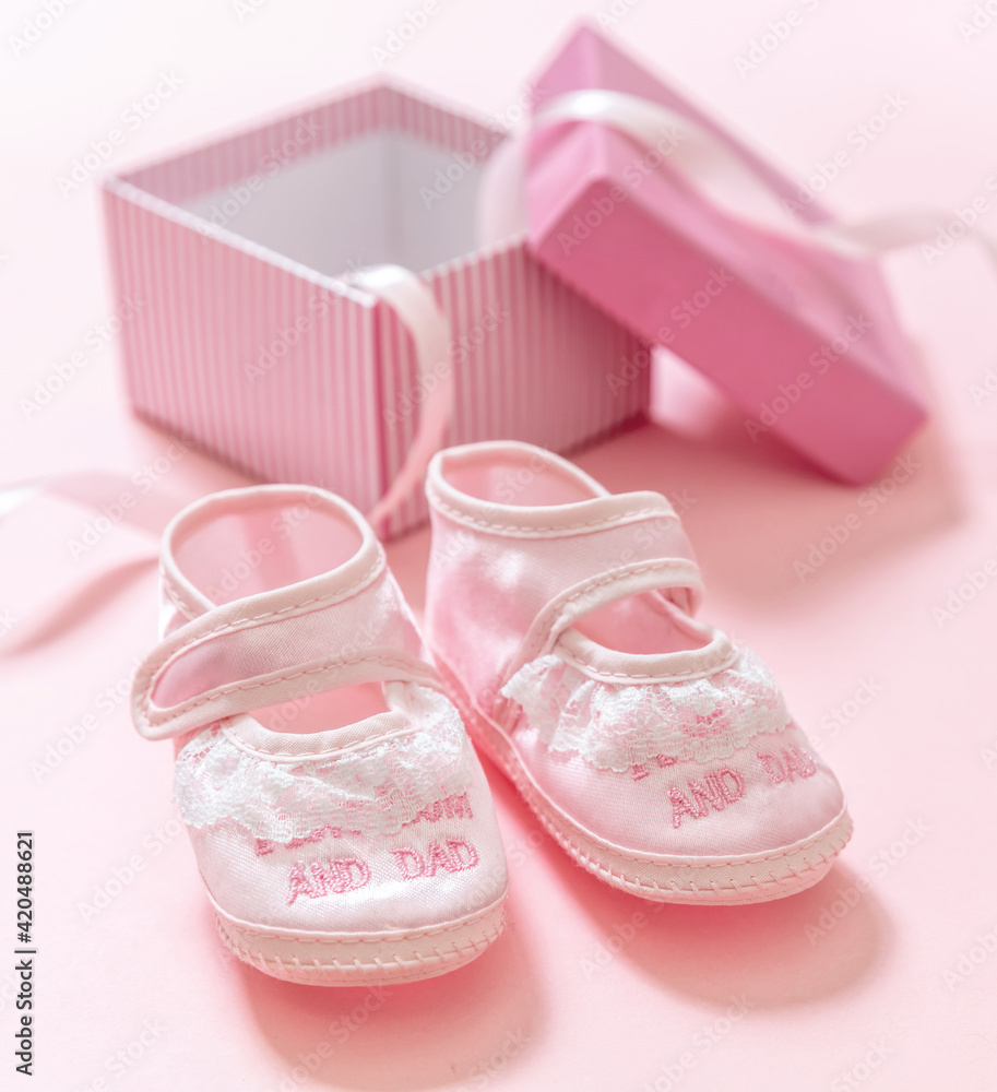 It’s a girl announcement. Baby girl pink shoes on pink color background. Baby shower, christening concept. It’s a girl announcement. Baby girl pink shoes on pink color background. Baby shower, christening concept.