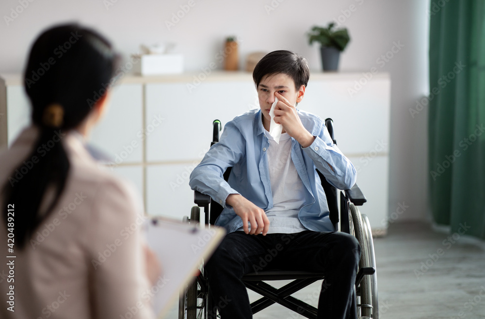 Professional psychologist working with disabled teenager in wheelchair at office - obrazy, fototapety, plakaty 