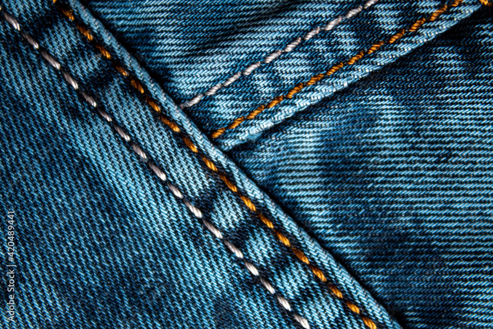 Background on the theme of denim clothing. Denim fabric with elements of seams. Background on the theme of denim clothing. Denim fabric with elements of seams.