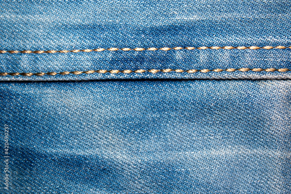 Background on the theme of denim clothing. Denim fabric with elements of seams. Background on the theme of denim clothing. Denim fabric with elements of seams.