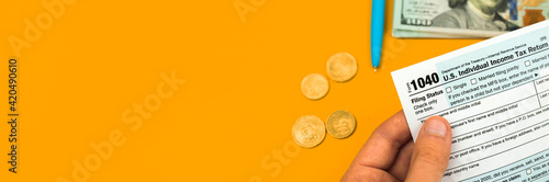 Man hand holds tax form 1040, income and return concept, business banner photo with copy space