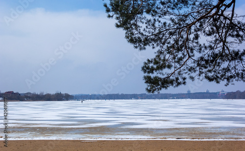 In early spring, a frozen lake in clear weather with a strip of sand. Europe © Sviatlana