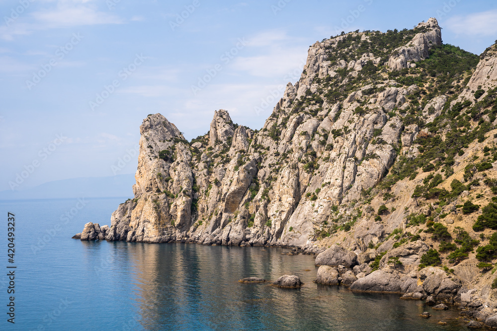Stone rock on the coast of the peninsula in Alanya (Turkey) - view from the sea. High bare desert steep cliff among the blue waters of the Mediterranean Sea, close-up