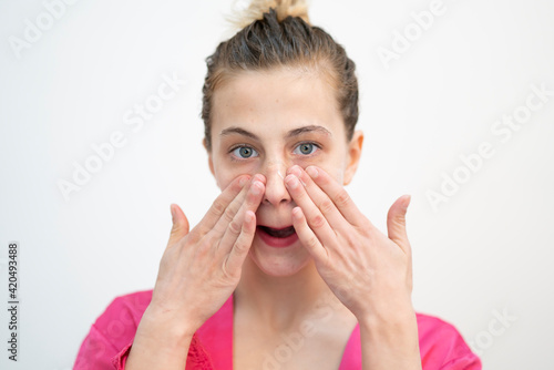 Happy Young Woman Applying Cream on Her Face, Studio Shot on White Background