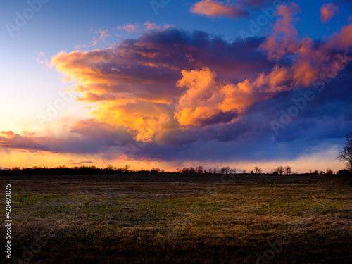 Dramatic Cloudscape. Dragon Shaped Pink Clouds at Sunset. Moody Stormy Sky over Green Field in Little Compton, Rhode Island.