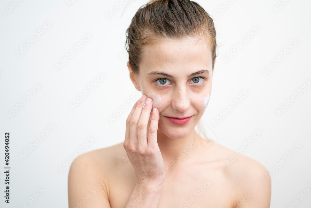 Happy Young Woman Applying Cream on Her Face, Studio Shot on White Background Happy Young Woman Applying Cream on Her Face, Studio Shot on White Background