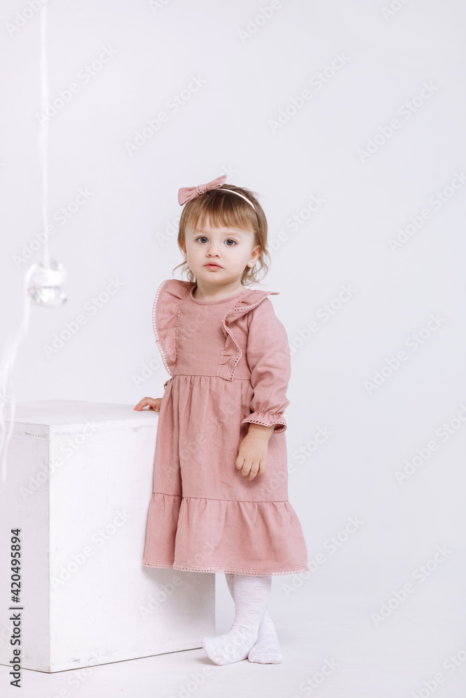 portrait of a little cute girl in a beautiful pink dress and bow on head is looking at the camera isolated on white background. adorable preschool age girl portrait of a little cute girl in a beautiful pink dress and bow on head is looking at the camera isolated on white background. adorable preschool age girl