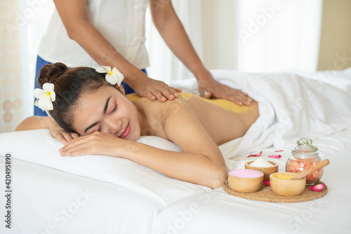 Beautiful Asian woman having exfoliation treatment with body scrub in spa salon, scrubbing and skin care concept, enjoying and relaxing time