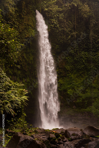 Waterfall landscape. Beautiful hidden waterfall in tropical rainforest. Foreground with big stones. Slow shutter speed, motion photography. Travel and adventure. Nung Nung waterfall, Bali