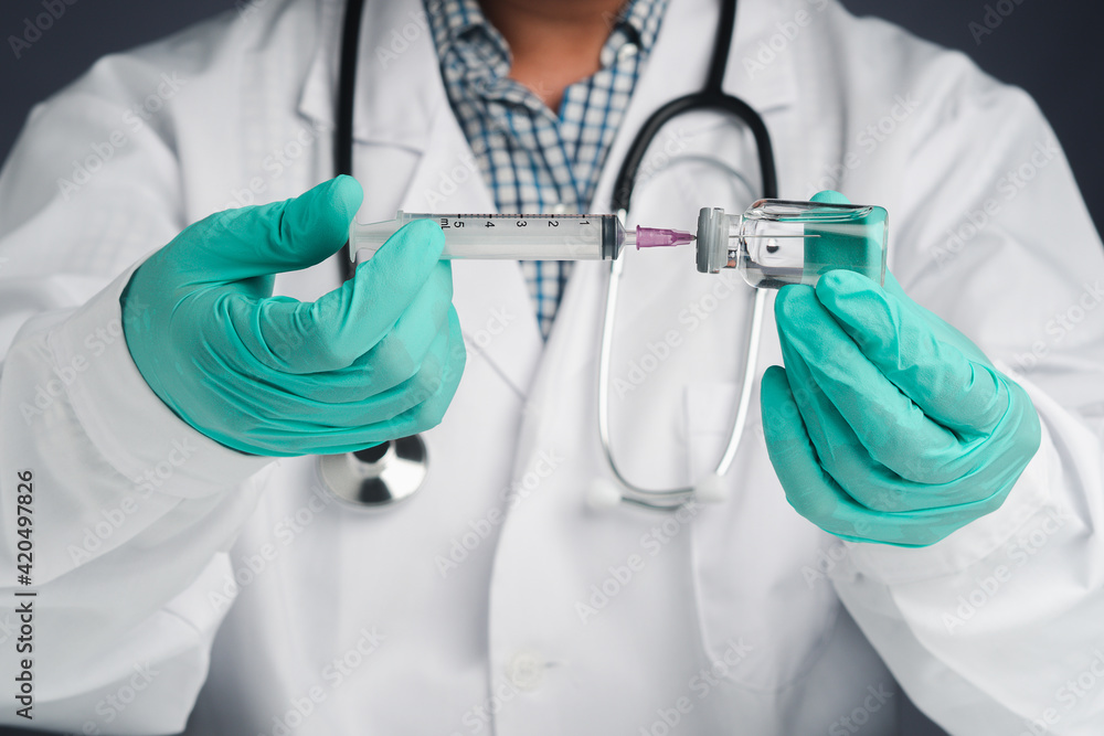 A doctor holding a syringe and vaccine bottle. Vaccine for immunization, and treatment from virus infection. Front view. Close-up photo. Concept of medical and the fight against the virus A doctor holding a syringe and vaccine bottle. Vaccine for immunization, and treatment from virus infection. Front view. Close-up photo. Concept of medical and the fight against the virus