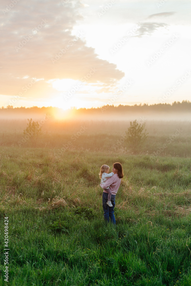 Mother and child standing in misty field during sunset Mother and child standing in misty field during sunset