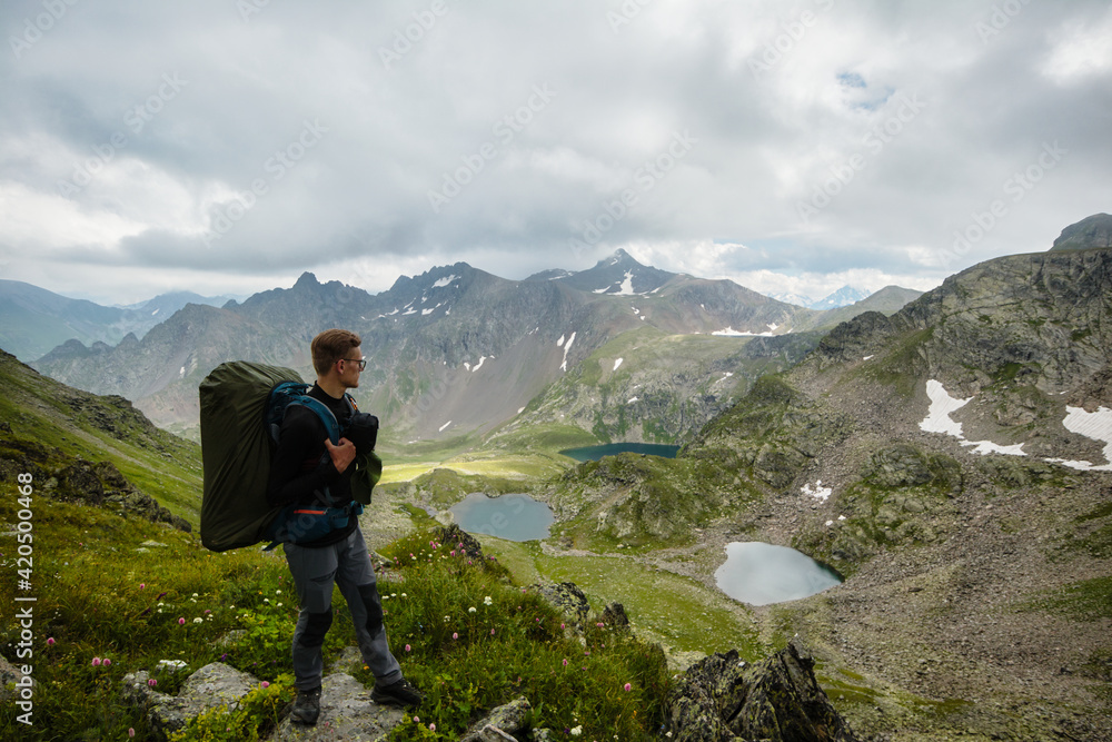 Young active man standing on cliff look at the mountain lakes. Travel and active life concept. Adventure and travel in the mountains region in the Russia