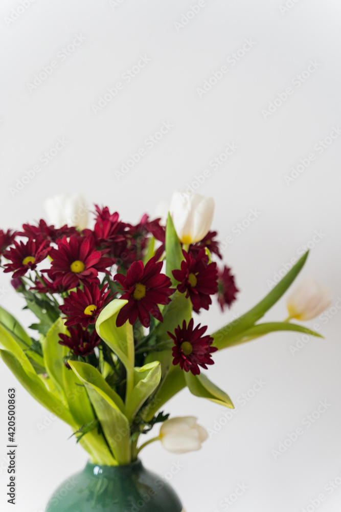 Bouquet of tulips and chrysanthemums in a vase on a white background. High-quality photo