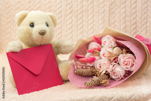 White teddy bear with flowers and envelope with congratulations.