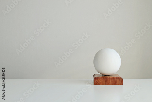Stylish interior mockup with white geometric shape of a ball on a  wooden stand, copy space