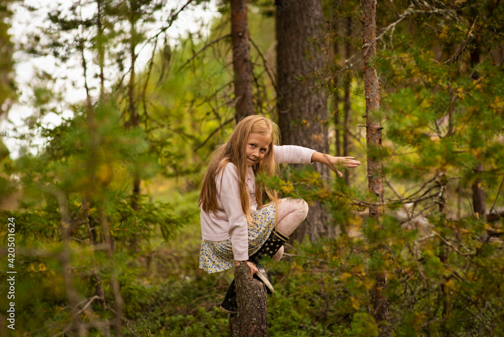 a 10-year-old girl with blonde hair climbed a tree in the forest, selective focus a 10-year-old girl with blonde hair climbed a tree in the forest, selective focus