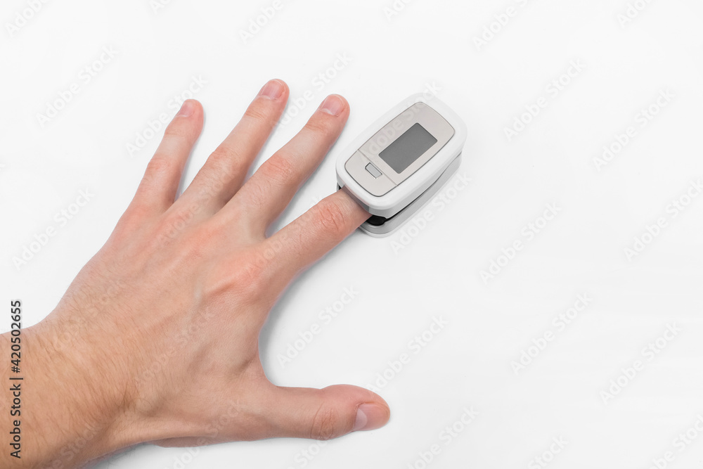 The guy's hand measures saturation with a modern medical device pulse oximeter on a white background The guy's hand measures saturation with a modern medical device pulse oximeter on a white background