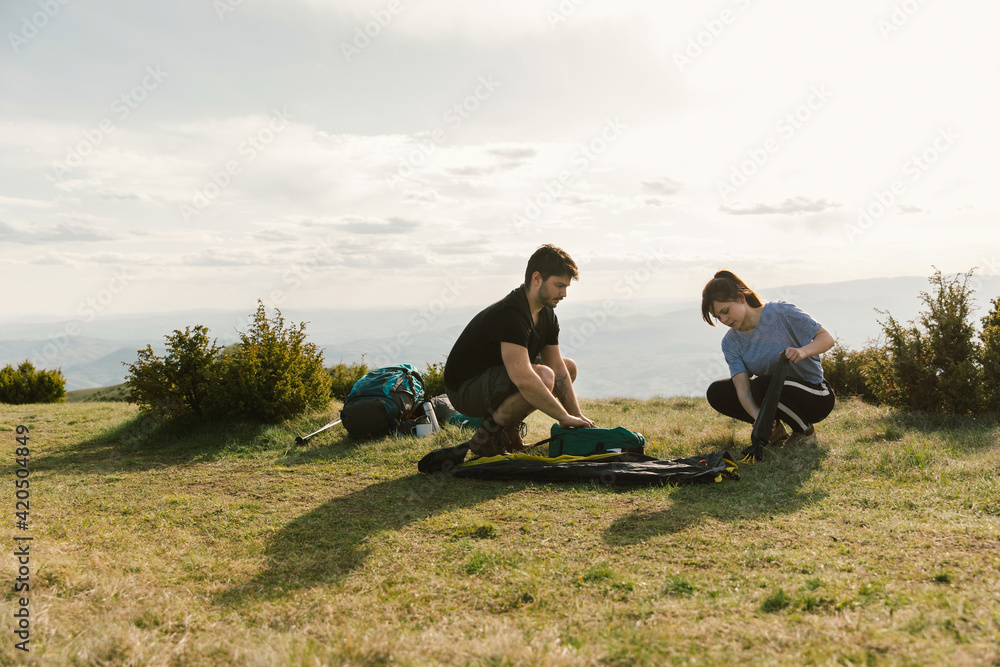 Young couple putting a tent together Young couple putting a tent together