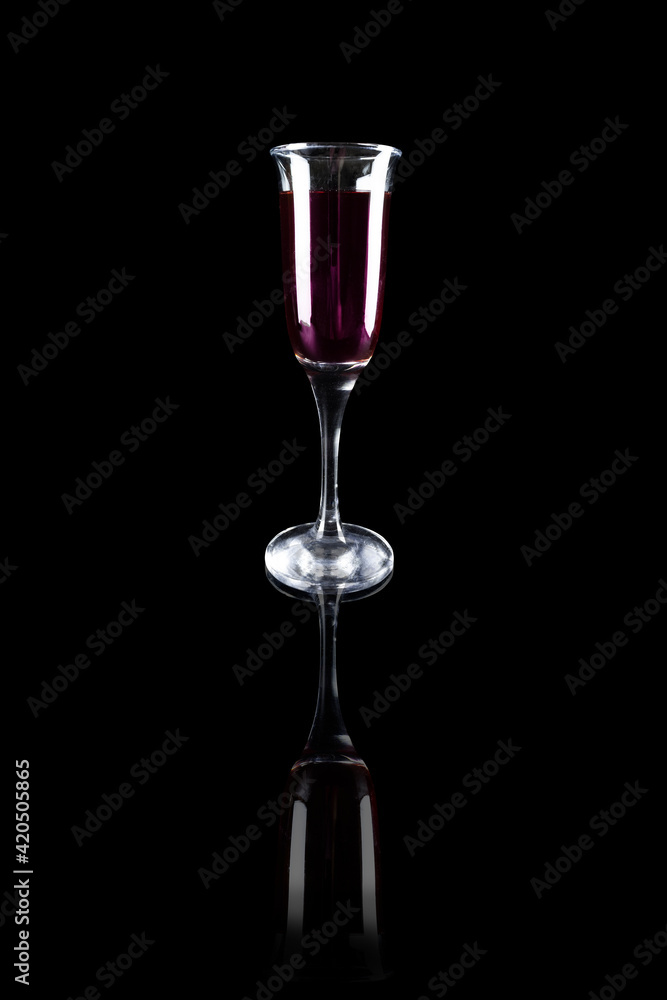 Transparent goblet with red wine on black reflective surface Transparent goblet with red wine on black reflective surface
