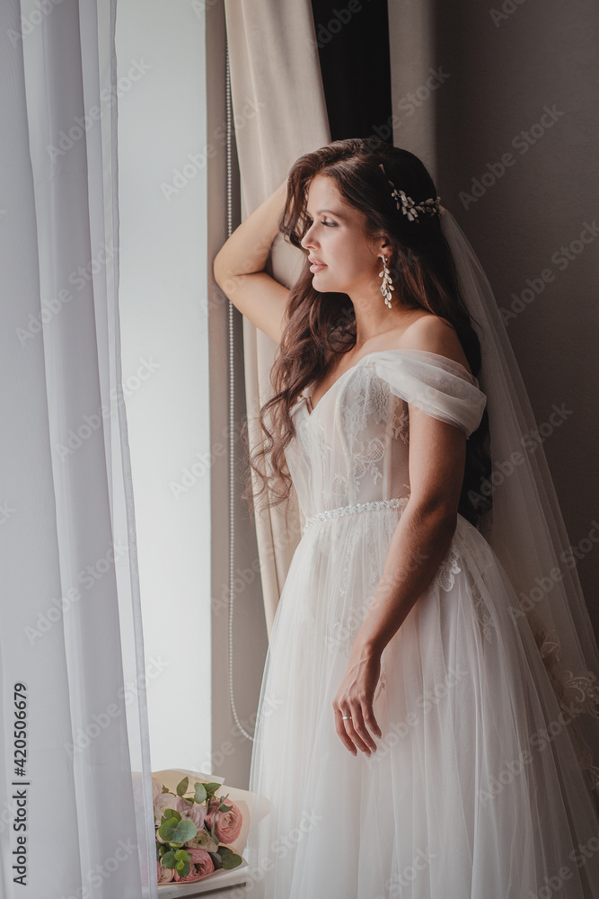 Young beautiful girl a brunette in a white wedding dress. Morning of the brite at the hotel Young beautiful girl a brunette in a white wedding dress. Morning of the brite at the hotel
