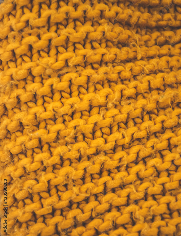 Fototapeta premium Closeup of woolen knitted textured fabric. Orange knitting pattern.