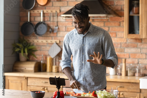 Cooking master class. Confident black man vlogger shoot tutorial teach audience to make healthy food. Young african guy capable cook broadcast live preparing national cuisine dish on domestic kitchen photo
