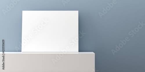 White empty poster or picture mock-up template on white sideboard in front of blue wall background