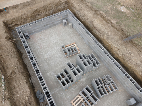 Aerial drone photo of a construction site for a pool, concrete blocks already coated and bricked up with construction adhesive in march