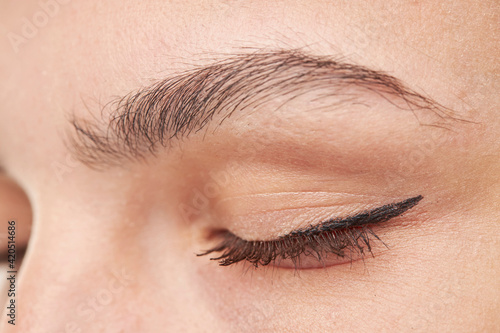 close-up portrait of young beautiful woman's closed eye zone make up with black arrow