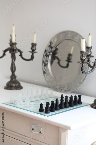Glass chessboard with black and white chess figures on white background.