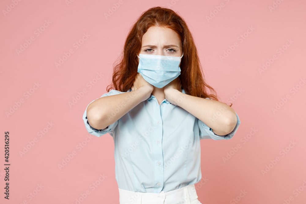 Young confused worried redhead woman 20s in blue shirt sterile face mask coronavirus virus covid-19 during pandemic quarantine hold hand behind neck isolated on pastel pink background studio portrait. Young confused worried redhead woman 20s in blue shirt sterile face mask coronavirus virus covid-19 during pandemic quarantine hold hand behind neck isolated on pastel pink background studio portrait.