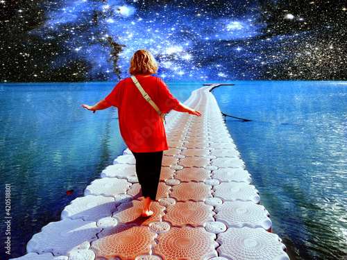 Surrealistic collage. A person walks along the ocean against the background of stars and galaxies