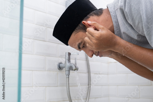Valokuva portrait of young Muslim man perform ablution (wudhu) before prayer at home