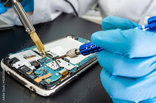 фотографія Technician repairing inside of mobile phone by soldering iron