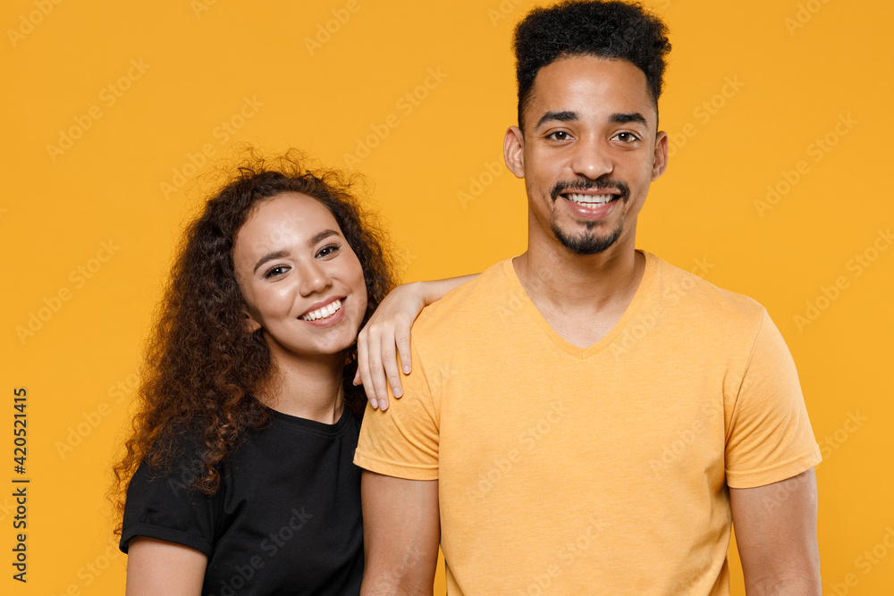 Obraz premium Young happy couple friends together family african smiling lovely woman man 20s wearing black t-shirt girlfiend lean on boyfriend isolated on yellow background studio portrait. Relationship concept.