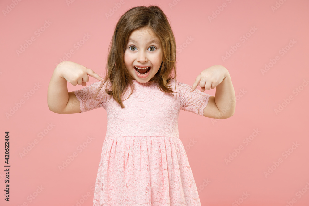 Little cute kid girl 5-6 years old wears rosy dress have fun pointing fingers on herself isolated on pastel pink background child studio portrait. Mother's Day love family childhood lifestyle concept. Little cute kid girl 5-6 years old wears rosy dress have fun pointing fingers on herself isolated on pastel pink background child studio portrait. Mother's Day love family childhood lifestyle concept.