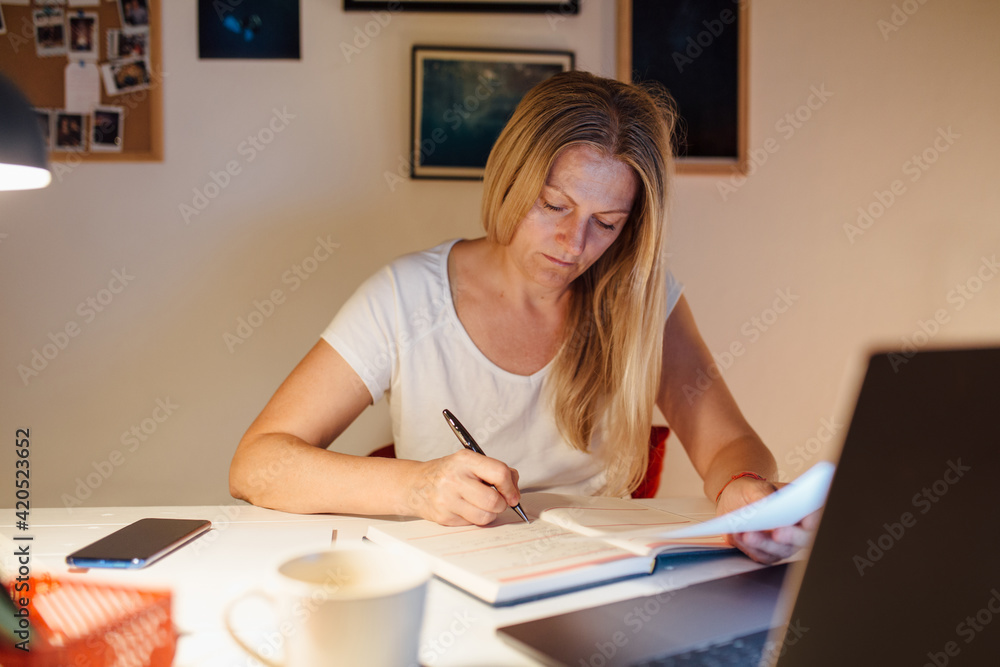 Woman Writing In Her Notebook At A Desk Woman Writing In Her Notebook At A Desk