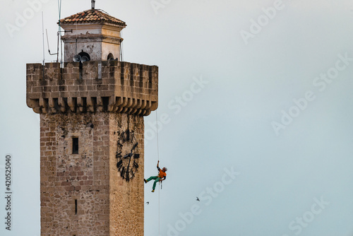 Climber rappelling down tower in city photo