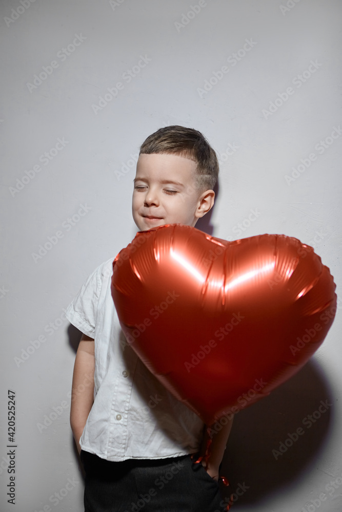 Valentine's day. Happy boy stands and holds red ball hearts on a white background. Valentine's day. Happy boy stands and holds red ball hearts on a white background.