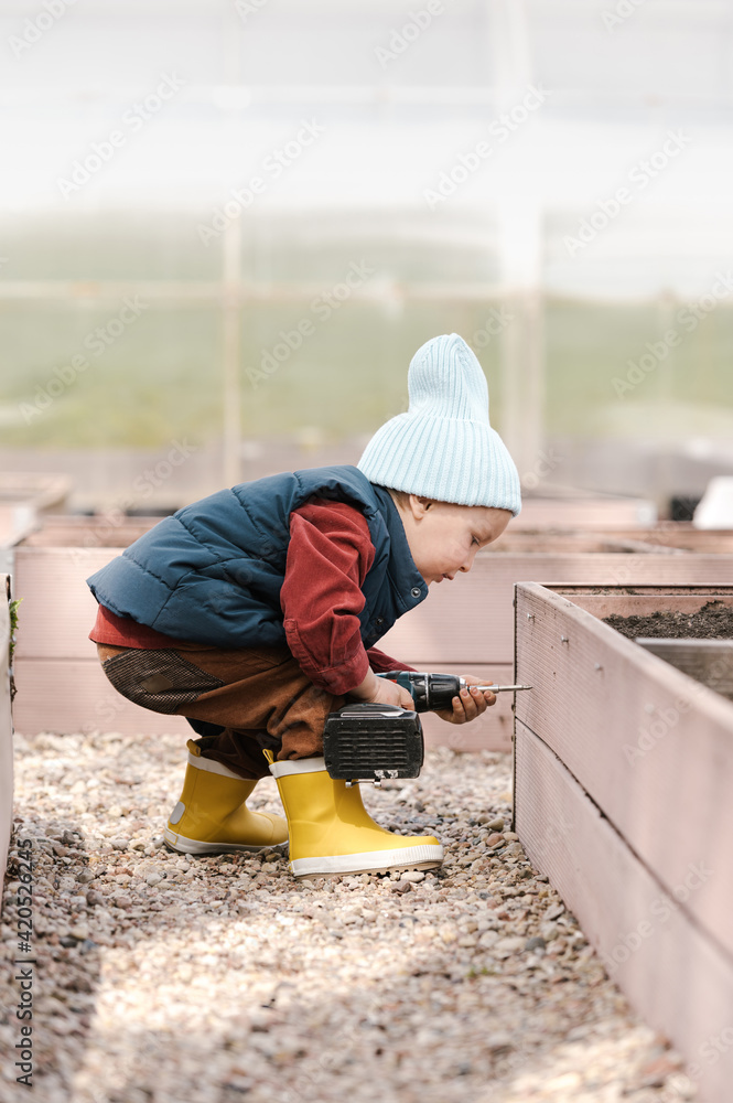Boy drilling garden bed in greenhouse Boy drilling garden bed in greenhouse