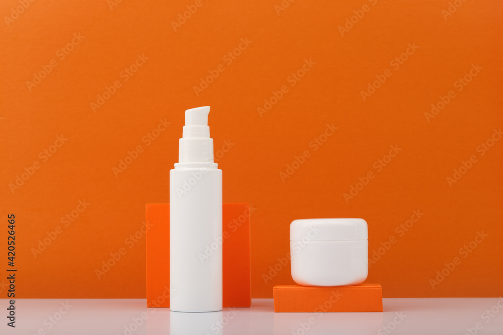 Face cream or lotion and under eye cream or serum with citrus extracts against orange background with copy space. Concept of organic skin care and beauty products with natural ingredients and oils Face cream or lotion and under eye cream or serum with citrus extracts against orange background with copy space. Concept of organic skin care and beauty products with natural ingredients and oils