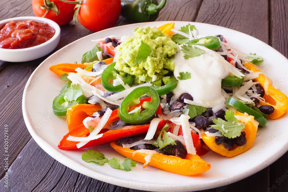 Healthy, plant based bell pepper nachos. Close up table scene on a dark wood background. Healthy, plant based bell pepper nachos. Close up table scene on a dark wood background.