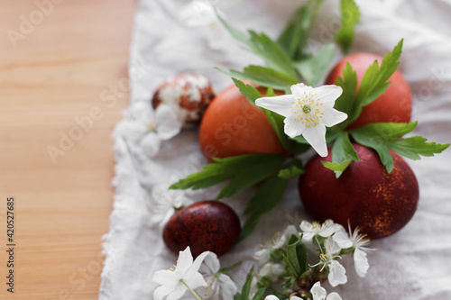 Modern red easter eggs with spring flowers on rustic linen cloth on wooden table. Happy Easter!