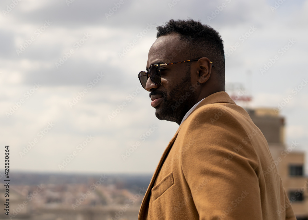 Elegant and confident black man model looking from a roof terrace. Madrid