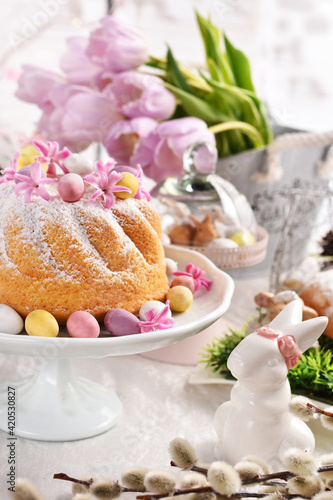 Easter ring cake with egg shaped candies and spring flower decoration on festive table